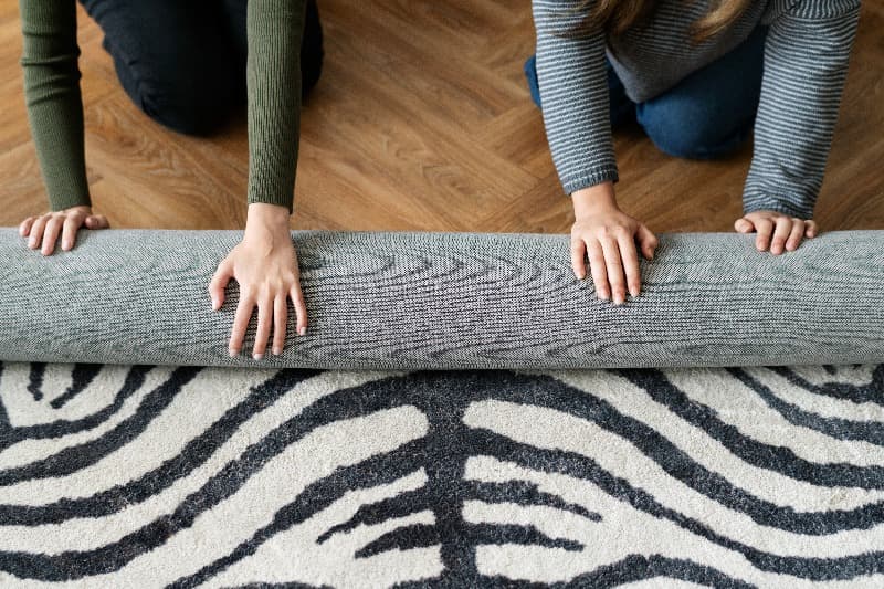 2 mujeres decorando su living con alfombra